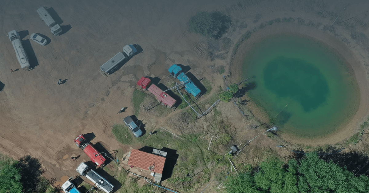 fotografia aérea mostra caminhões-pipa abastecendo uma estação de coleta água