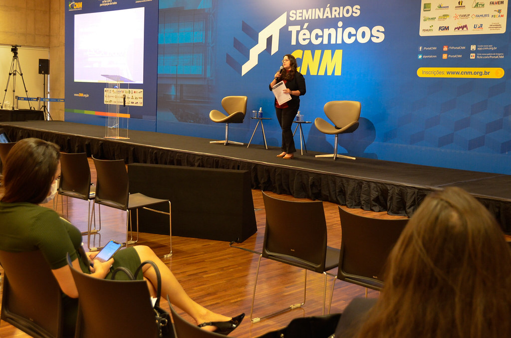 Foto de mulher dando palestra no seminário do CNM sobre o Marco Legal do Saneamento