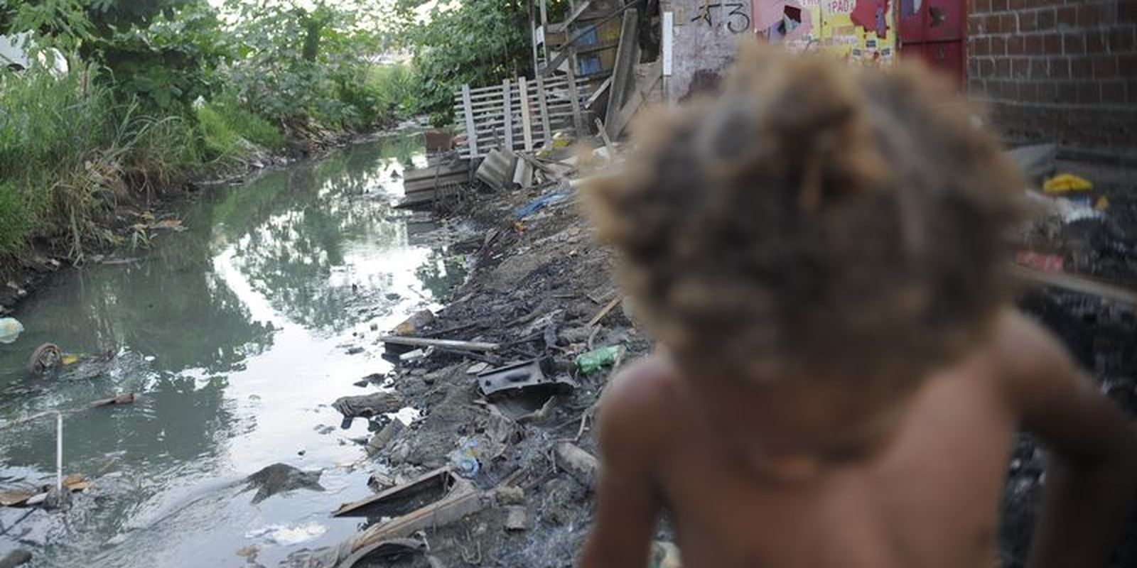 Criança perto de esgoto no Complexo da Maré, no Rio de Janeiro / Crédito: Fernando Frazão - Agência Brasil
